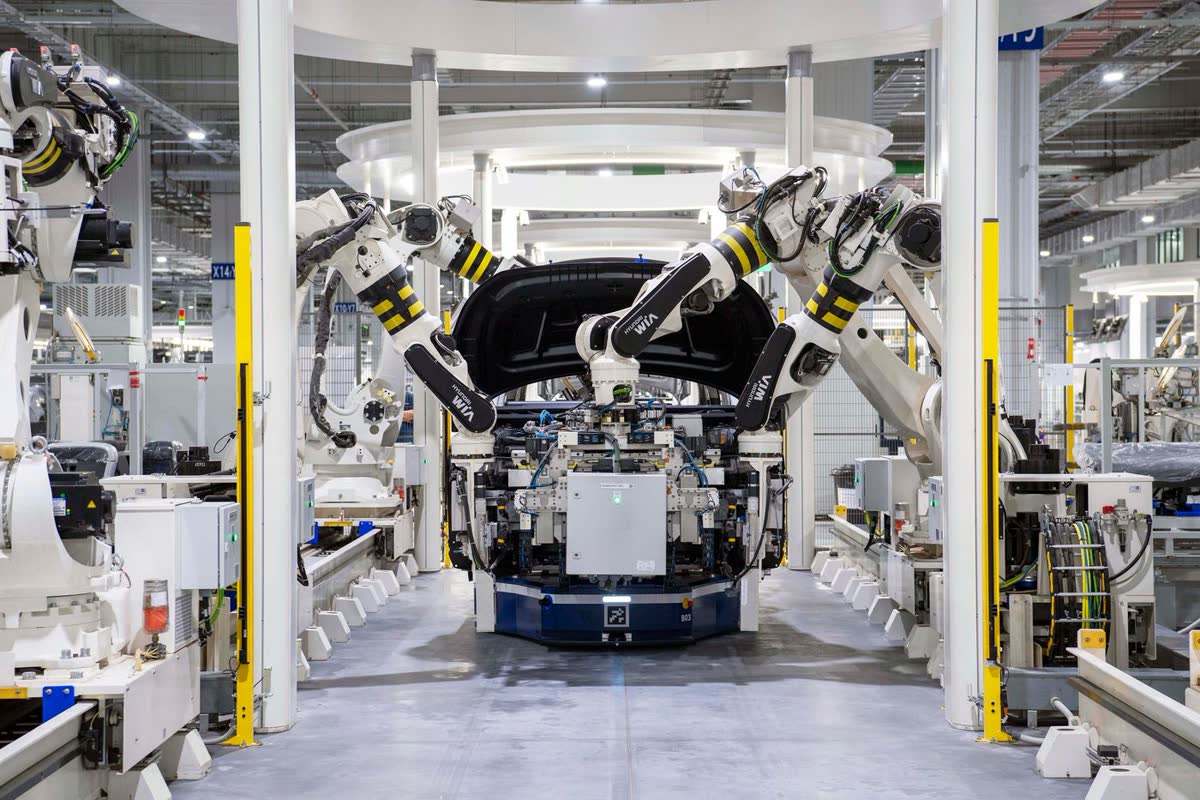 Celda de ensamblaje automatizada con brazos rob&oacute;ticos trabajando sobre una l&iacute;nea de producci&oacute;n.