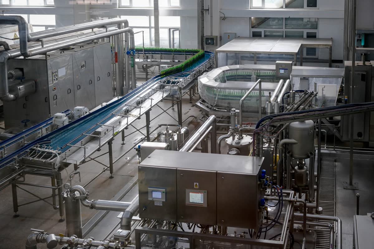 Línea de proceso en una planta de alimentos: cintas transportadoras, equipos de acero inoxidable y tableros de control.